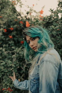 Portrait of young woman with dyed hair standing by plants
