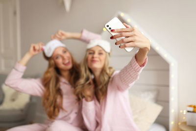 Happy people women in pajamas make selfie on the phone using technology