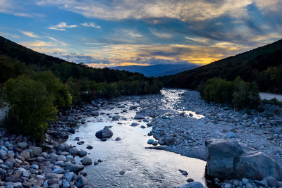 Stones on shore against sky during sunset