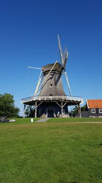 Traditional windmill on field against clear blue sky