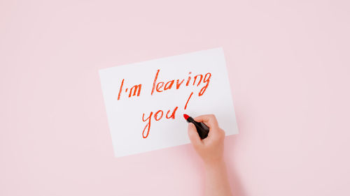 Midsection of woman holding paper against white background