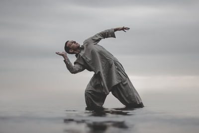 Man exercising in sea against sky