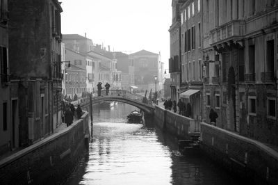 Canal amidst city against sky