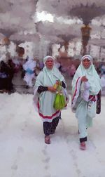 Rear view of people walking on snow covered landscape