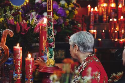 Senior woman with lit candles in temple