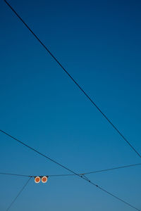 Low angle view of power lines against clear blue sky