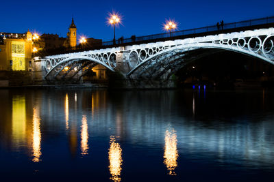 Arch bridge over river at night