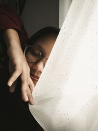 Young woman hiding behind curtain