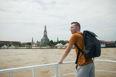Traveler with backpack is enjoy view from ferry boat to temple wat arun in bangkok. 