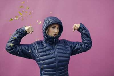 Full length of man holding umbrella against pink background