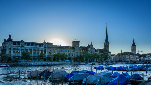 Boats moored in river with buildings in background
