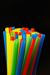 Close-up of colorful drinking straws against black background