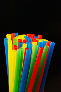 Close-up of colorful drinking straws against black background