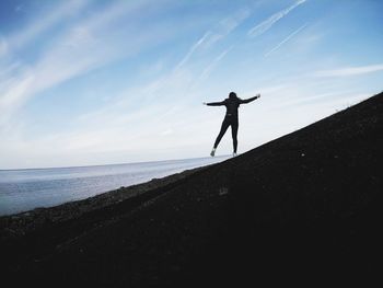 Silhouette man standing on beach against sky