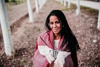 Portrait of smiling woman holding coffee cup sitting at park