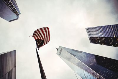 Low angle view of american flag amidst buildings against sky