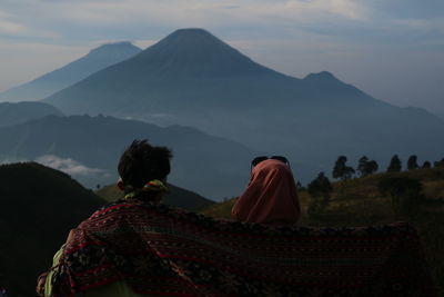 Rear view of people on mountain against sky