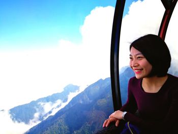 Smiling woman looking at mountains against sky