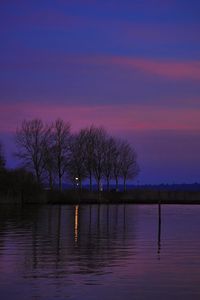 Silhouette trees by lake against romantic sky at sunset