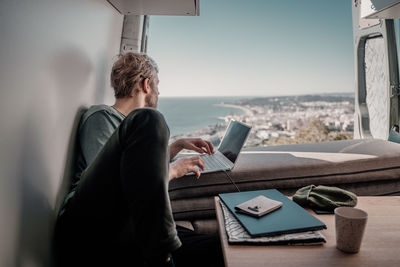 Man using laptop sitting by window