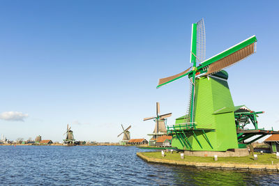 Windmills by the lake against blue sky