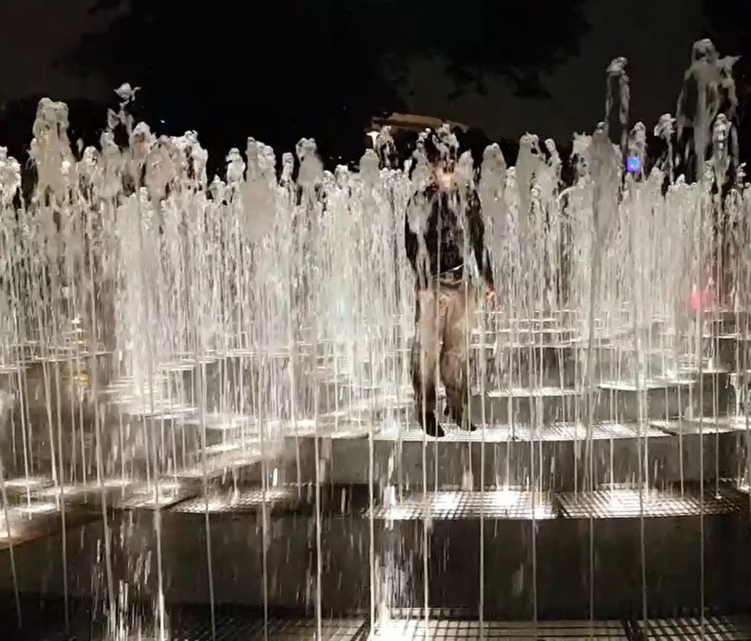 REFLECTION OF MAN SWIMMING IN ILLUMINATED WATER