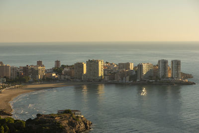 Sea by buildings against sky in city