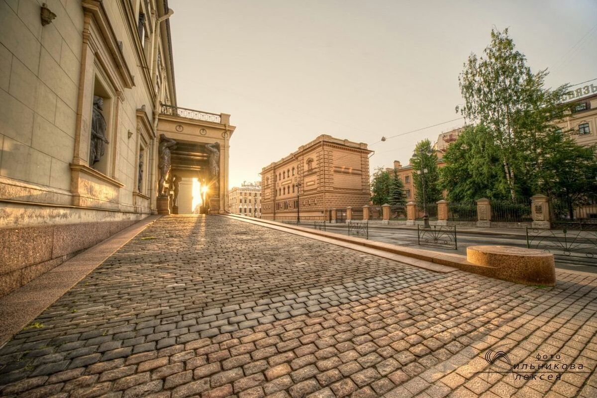 architecture, building exterior, built structure, the way forward, cobblestone, city, clear sky, sky, paving stone, history, sunlight, travel destinations, walkway, footpath, building, outdoors, famous place, steps, street, no people