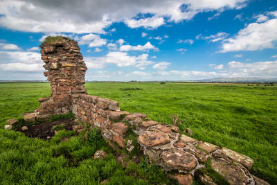 Scenic view of ruin on field against sky