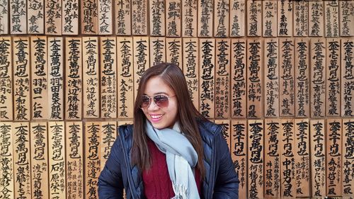 Portrait of a smiling young woman standing against wall