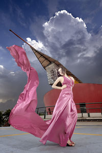 Woman holding pink umbrella against sky