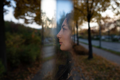 Portrait of young woman standing against trees