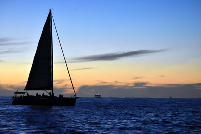 Silhouette sailboat sailing on sea against sky during sunset