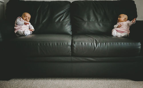 Siblings sitting on sofa at home