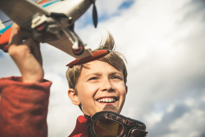 Boy playing with toy airplane against sky