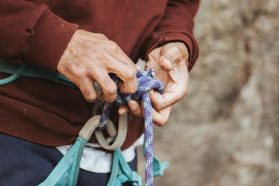Man tying a knot in a rope to prepare for outdoor rock climbing