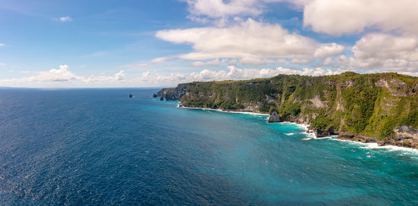 Blue sea washes rocky mountains covered forest. separate rocks in water. klungkung, indonesia