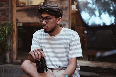 Young man looking away while sitting outdoors