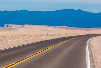 Road by desert against clear sky