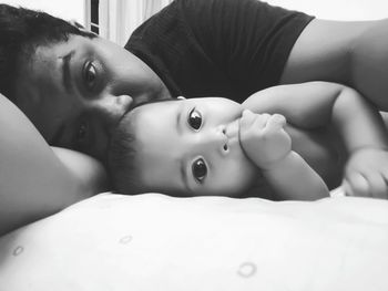 Close-up portrait of baby girl lying on bed at home