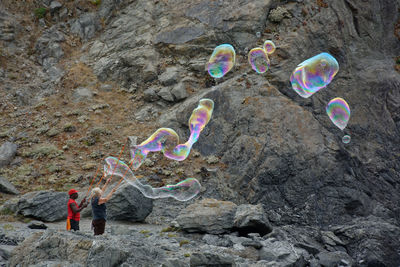 People blowing bubbles against rock formation