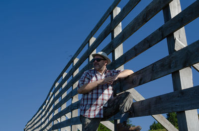 Low angle view of man standing against clear blue sky