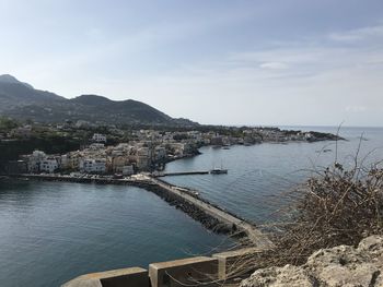 Aerial view of city by sea against sky