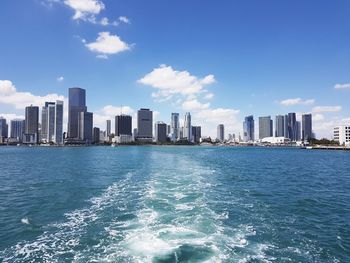 Sea by buildings in city against sky