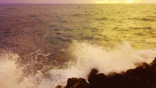 Waves splashing on shore against sky