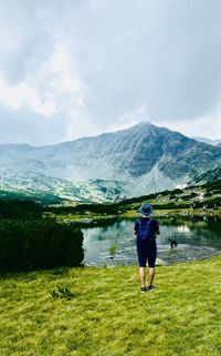 Rear view of man standing by lake against sky