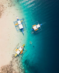 A bird's eye drone view of three large boats and one small boat parked on a beach