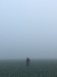 People on field against sky during foggy weather