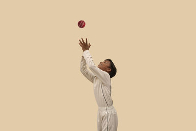 Man playing with ball against gray background