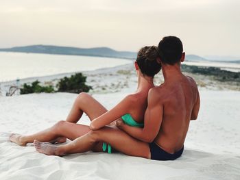 Side view of couple sitting on beach